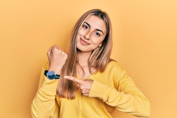 Canvas Print - Beautiful hispanic woman wearing casual yellow sweater in hurry pointing to watch time, impatience, looking at the camera with relaxed expression