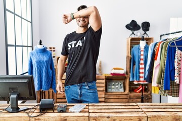 Sticker - Young hispanic man working at retail boutique smiling cheerful playing peek a boo with hands showing face. surprised and exited