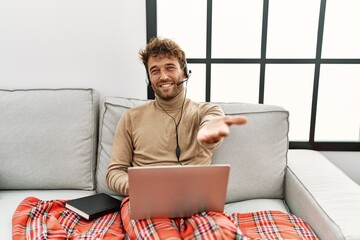 Wall Mural - Young handsome man with beard wearing operator headset working from home smiling cheerful offering palm hand giving assistance and acceptance.