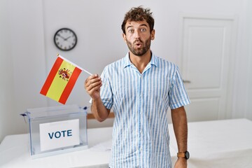 Sticker - Young handsome man at political campaign election holding spain flag scared and amazed with open mouth for surprise, disbelief face