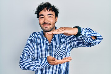 Poster - Young hispanic man wearing casual clothes gesturing with hands showing big and large size sign, measure symbol. smiling looking at the camera. measuring concept.