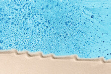 Blue Water And White Beach Sand Concept, Flat Lay. Background For Tropical Travel Or Skincare Cosmetics.