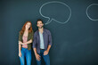 © Daniel L/peopleimages.com - She likes a man who speaks his mind. Portrait of a young couple standing in front of a blackboard with speech bubbles drawn on it.