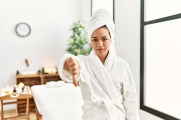 Sticker - Young brunette woman wearing towel and bathrobe standing at beauty center looking unhappy and angry showing rejection and negative with thumbs down gesture. bad expression.