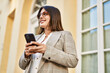 © Krakenimages.com - Young hispanic businesswoman smiling happy using smartphone at the city.