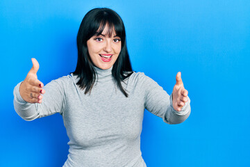 Sticker - Young hispanic woman wearing casual clothes looking at the camera smiling with open arms for hug. cheerful expression embracing happiness.