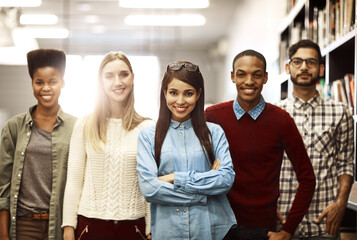 Fototapete - Our successful careers start with a good education. Portrait of a group of university students standing together in the library on campus.