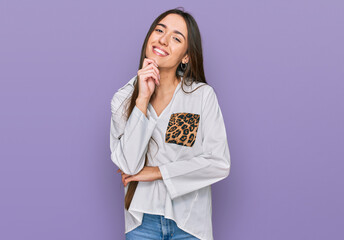 Poster - Young hispanic girl wearing casual clothes looking confident at the camera with smile with crossed arms and hand raised on chin. thinking positive.