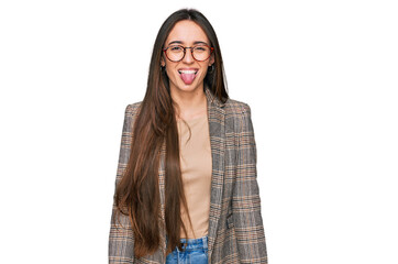 Poster - Young hispanic girl wearing business clothes and glasses sticking tongue out happy with funny expression. emotion concept.