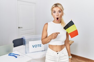 Poster - Young caucasian woman at political campaign election holding belgium flag scared and amazed with open mouth for surprise, disbelief face