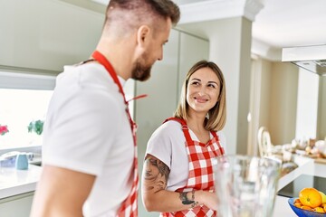 Wall Mural - Young couple smiling confident making smoothie cooking at kitchen