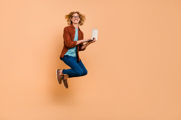 Poster - Full length body size view of handsome trendy cheerful guy jumping writing email isolated over beige pastel color background