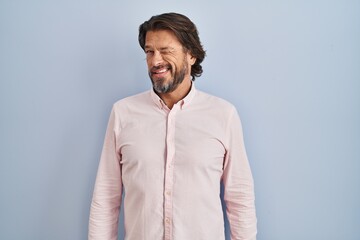 Sticker - Handsome middle age man wearing elegant shirt background winking looking at the camera with sexy expression, cheerful and happy face.