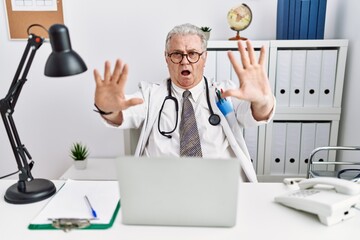 Wall Mural - Senior caucasian man wearing doctor uniform and stethoscope at the clinic doing stop gesture with hands palms, angry and frustration expression