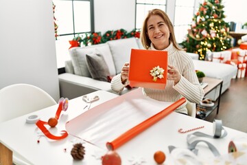 Poster - Middle age caucasian woman smiling confident holding christmas gift at home