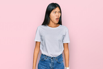 Poster - Beautiful young asian woman wearing casual white t shirt angry and mad screaming frustrated and furious, shouting with anger. rage and aggressive concept.