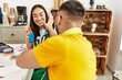© Krakenimages.com - Young hispanic couple smiling happy playing with painted hands sitting on the table at art studio.