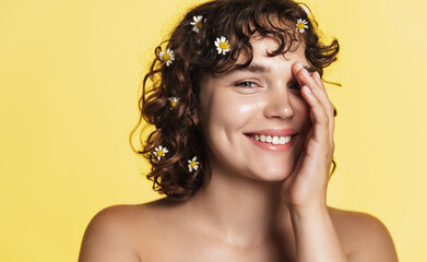Wall Mural - Skin care and women beauty. Happy naked female holding chamomile and smiling. Promo of facial products for soothing, hydration and redness treatment using active botanical ingridients