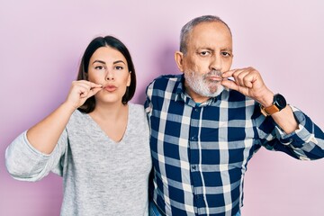 Sticker - Hispanic father and daughter wearing casual clothes mouth and lips shut as zip with fingers. secret and silent, taboo talking