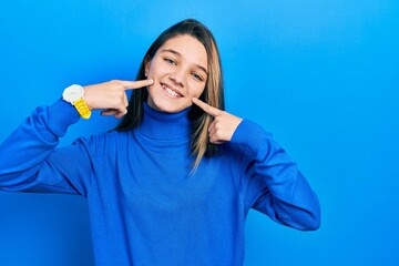 Poster - Young brunette girl wearing turtleneck sweater smiling cheerful showing and pointing with fingers teeth and mouth. dental health concept.