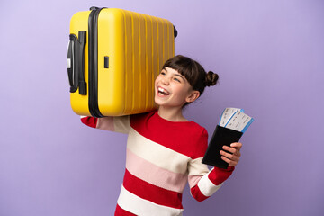 Wall Mural - Little caucasian girl isolated on purple background in vacation with suitcase and passport