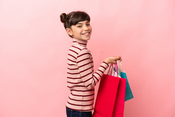 Wall Mural - Little caucasian girl isolated on pink background holding shopping bags and smiling