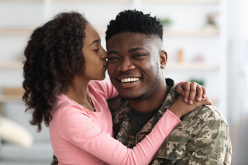 Portrait of happy african american teen girl kissing dad soldier