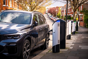 Wall Mural - An electric car on-street charging on residential street