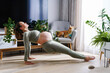 Pregnant female doing prenatal yoga at home in the living room in the early morning. Morning rituals. Expecting mom