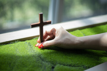 Hand holding wooden cross with blur background.