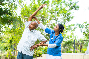 Nurse helping senior old man helping to do exercise at nursing home - concept of caretaker, well-being and rehabilitation