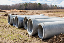 Reinforced Concrete Storm Sewer Pipes Of Large Diameter Stacked At A Construction Site. Sewer Large Diameter Pipes. Wastewater Disposal In A Modern City.