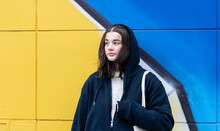 A Young Woman Against A Yellow-blue Wall, Urban Graffiti.