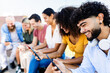 © Xavier Lorenzo - Group of millennial friends using smartphones sitting outdoors - Young diverse people watching social media content on mobile devices