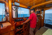 Captain On A Wooden Sailboat Steering His Vessel
