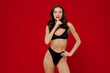 © ViDi Studio - Young brunette woman 20s with perfect fit body wear black underwear say hush be quiet with finger on lips shhh gesture isolated on plain red background studio portrait. People female beauty concept.