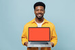 © ViDi Studio - Young happy man of African American ethnicity 20s wear yellow shirt hold use work on laptop pc computer with blank screen workspace area isolated on plain pastel light blue background studio portrait