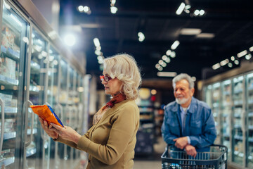 Wall Mural - Senior couple choosing groceries in supermarket