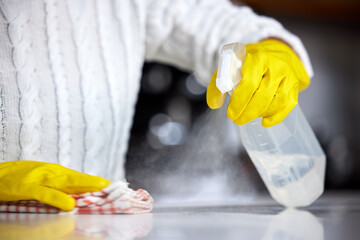 Wall Mural - Always use a strong disinfectant. Shot of a woman spraying her kitchen counter to clean it.