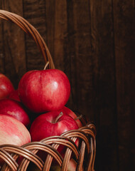 Wall Mural - Fresh ripe red apples in a wicker basket on a wooden background. Organic raw food. Vegan concept. Healthy eating concept. Side view.