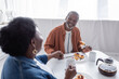 joyful and senior african american couple holding hands while having breakfast.