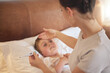 © Kirsten D/peopleimages.com - You definitely have a fever. Shot of a woman taking her little boys temperature with a thermometer in bed at home.