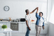 © LIGHTFIELD STUDIOS - retired african american couple smiling while dancing in kitchen.