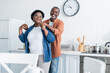 © LIGHTFIELD STUDIOS - happy senior african american man holding hands of smiling wife in kitchen.