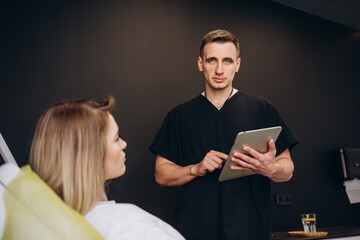 Wall Mural - Friendly doctor and patient woman discussing current health examination while sitting in sunny clinic. Medicine concept