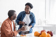 © LIGHTFIELD STUDIOS - happy african american wife serving coffee to smiling husband during breakfast.