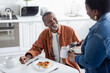 © LIGHTFIELD STUDIOS - happy african american man looking at wife serving coffee during breakfast.