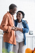 © LIGHTFIELD STUDIOS - happy and senior african american couple holding hands in kitchen.
