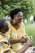 © LIGHTFIELD STUDIOS - happy and senior african american couple laughing while holding glasses of wine.