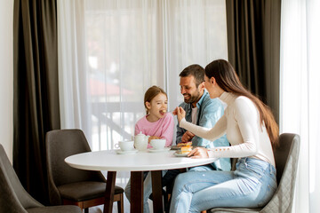 Wall Mural - Happy young famila eat cakes and drink tea together